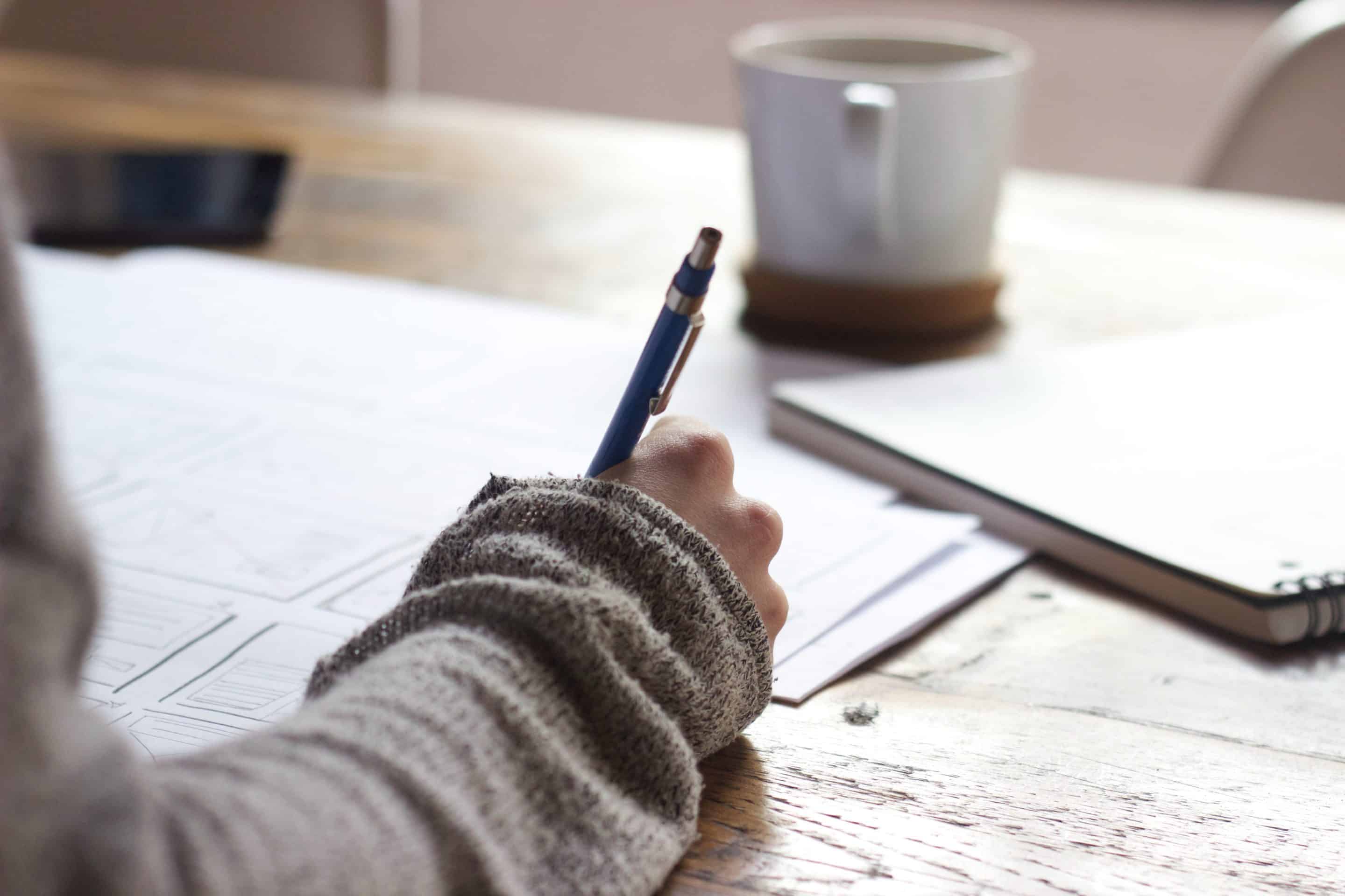 Person writing on a piece of paper with a pen